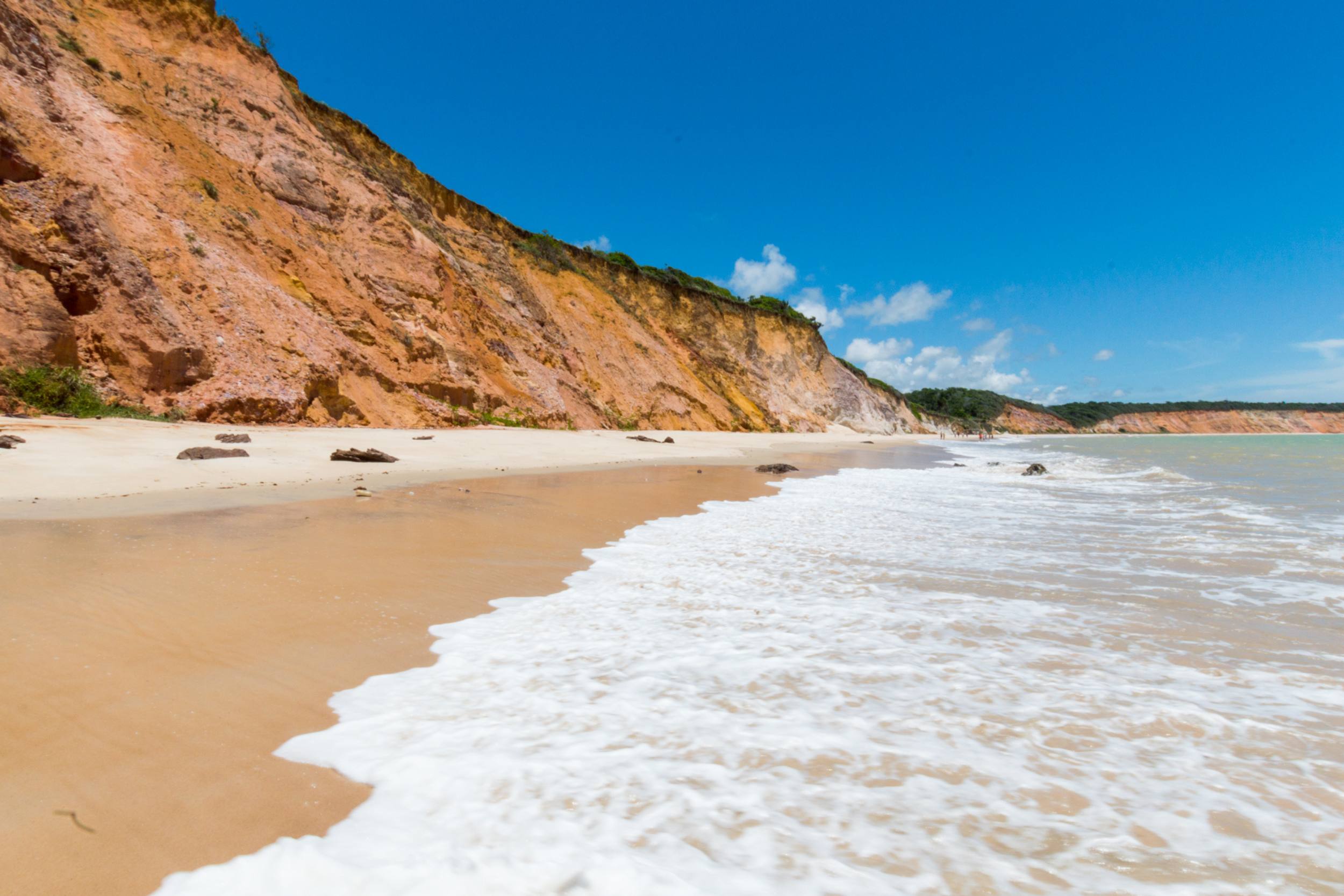 Falésias da praia de Carro Quebrado e espuma das ondas quebrando na areia