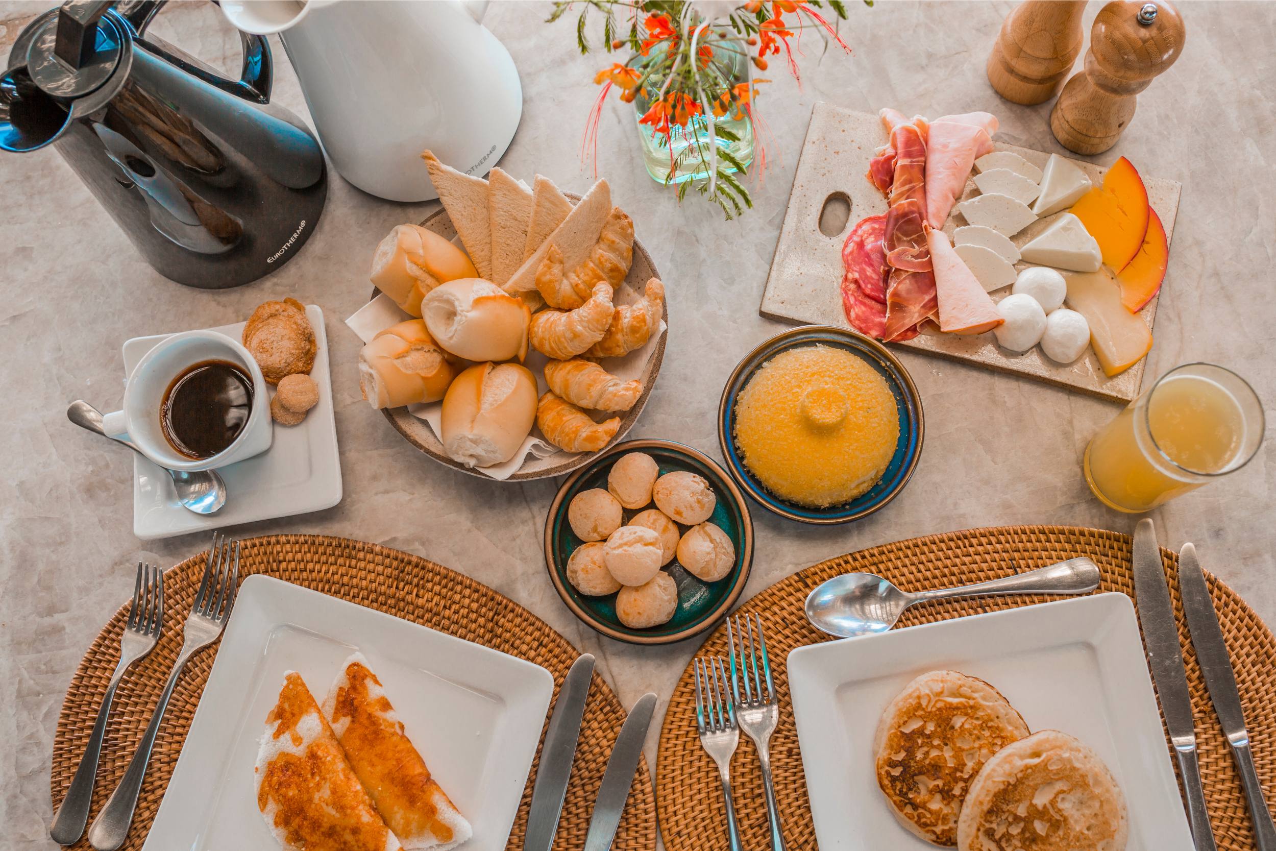 mesa de café da manhã da pousada, com tapiocas e panquecas frescas, frios, pães, café e típico cuscuz nordestino