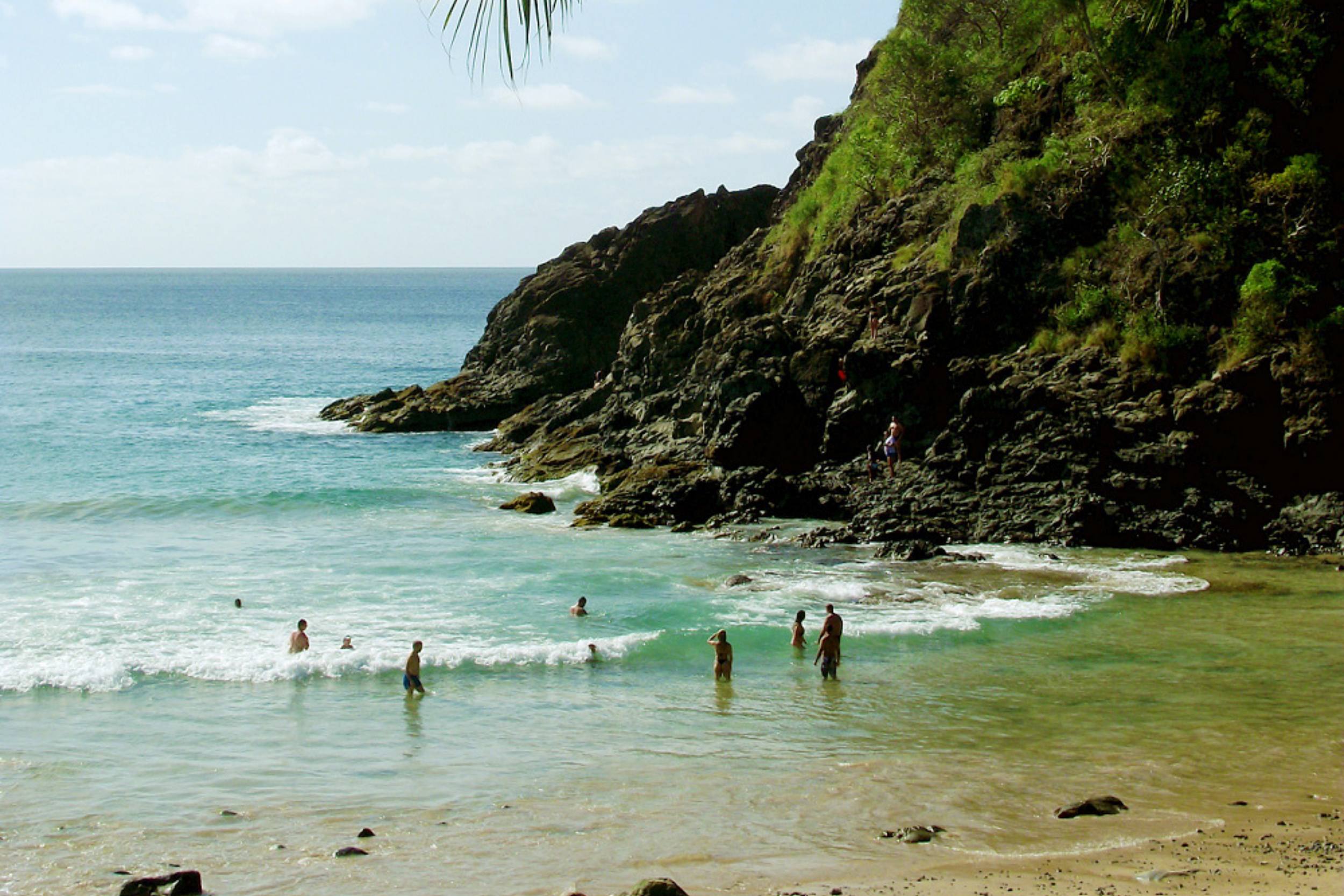 Turistas na lateral direita da Praia do Cachorro, onde há formações rochosas.