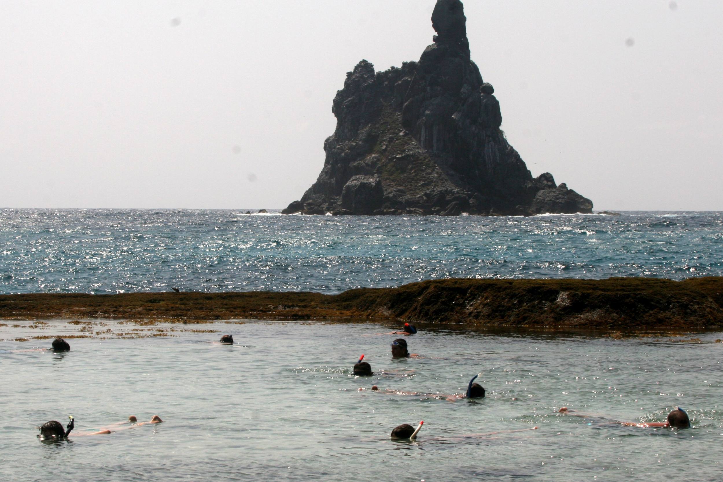 A foto mostra pessoas fazendo mergulho de flutuação na piscina natural do Atalaiaaia