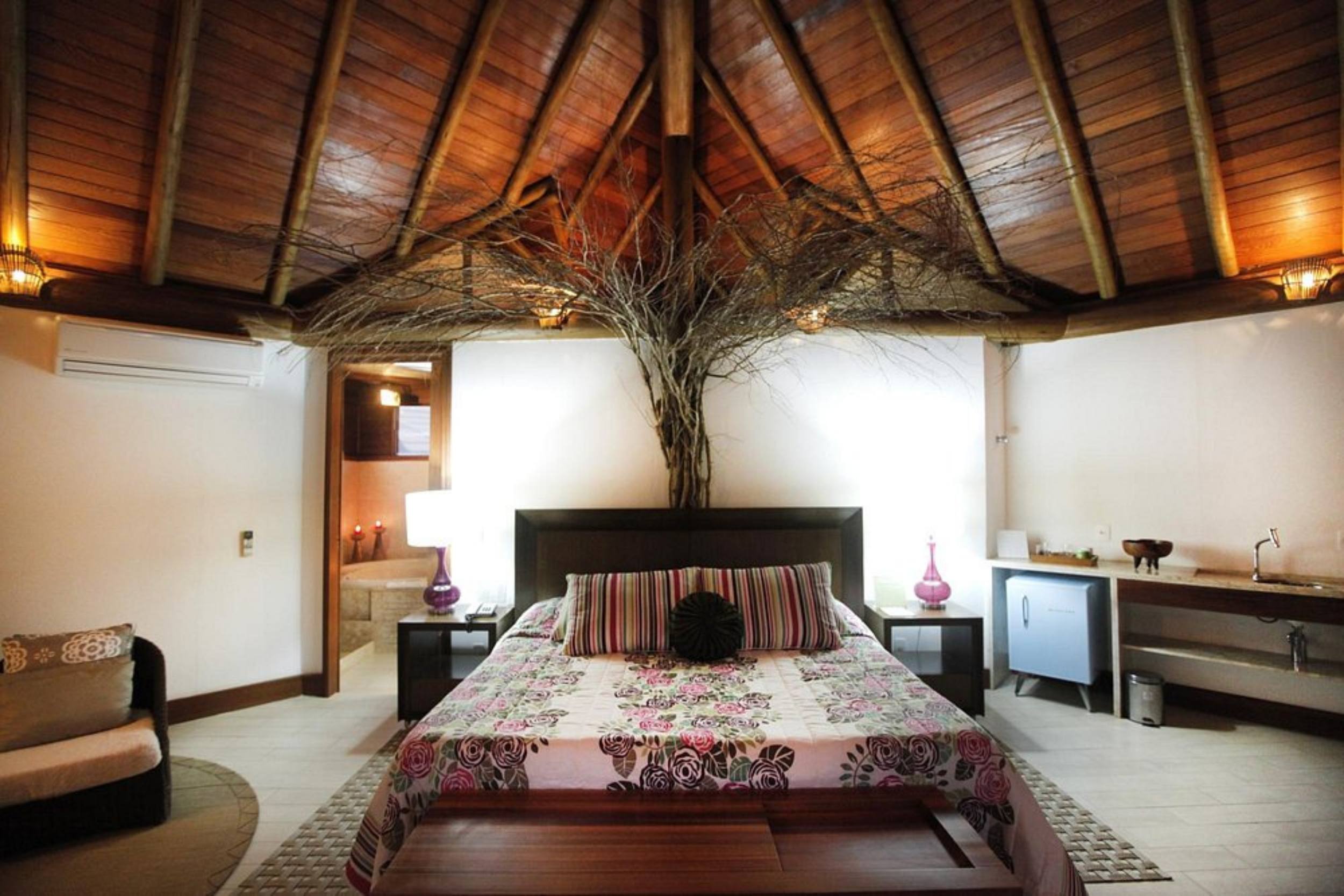 Quarto amplo com cama de casal e alto pé direito.